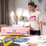 A young lady using a pink dtf printer in her studio with various printing apparel items on a table